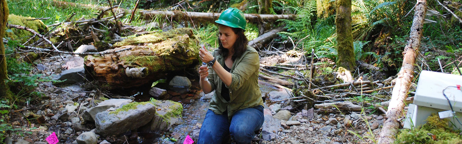 woman kneeling in forest examining sample