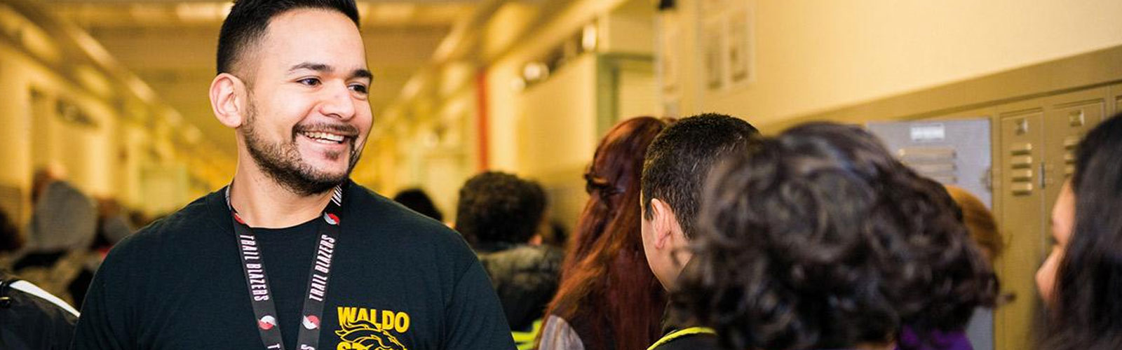 man working in an elementary school surrounded by young students