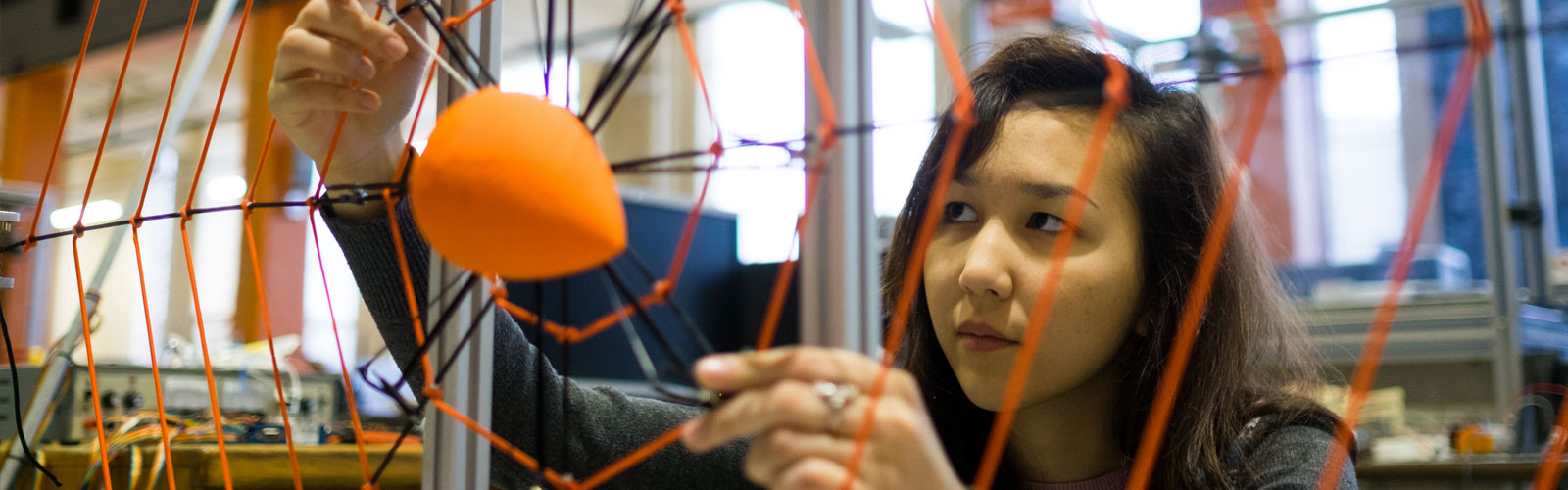 woman building orange web-like structure